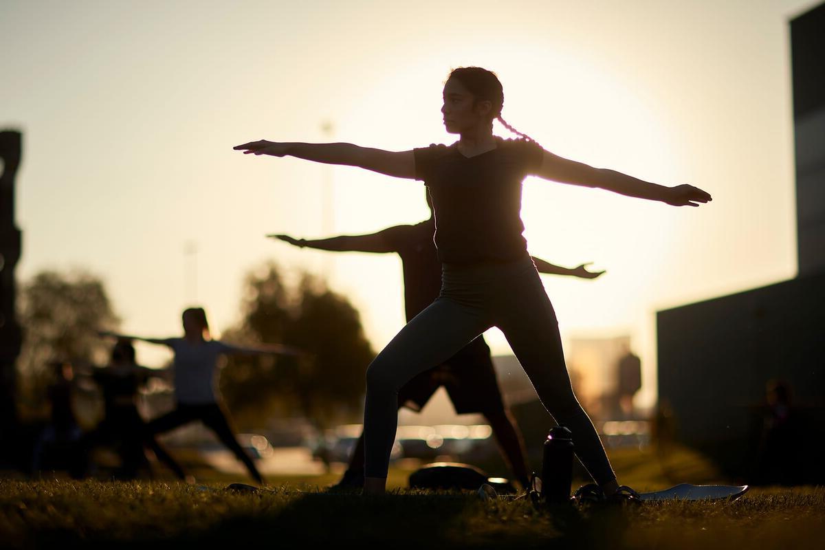 学生 perform yogoa outside suring sunset