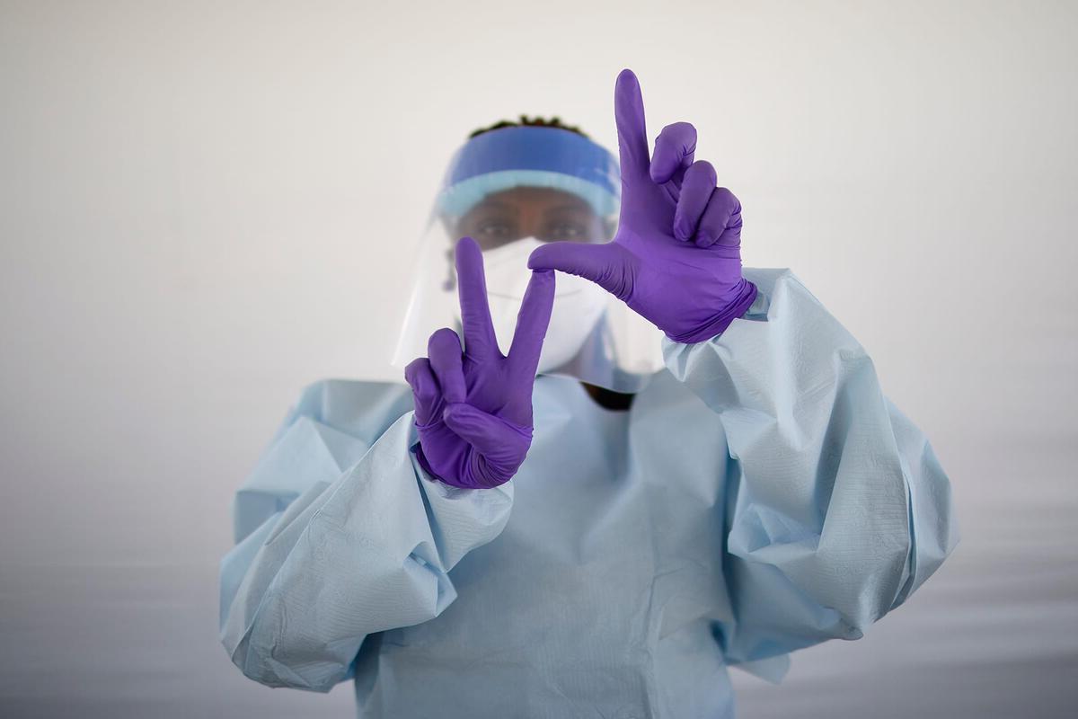School of Medicine staff member in scrubs making L.V. sign with hands