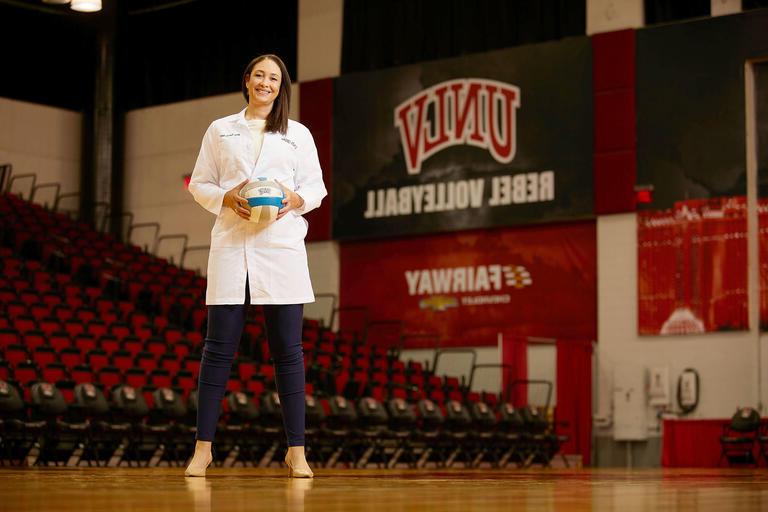 woman in dentist coat holding volleyball on a court