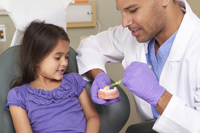 儿科牙医向一个小病人展示牙齿模型